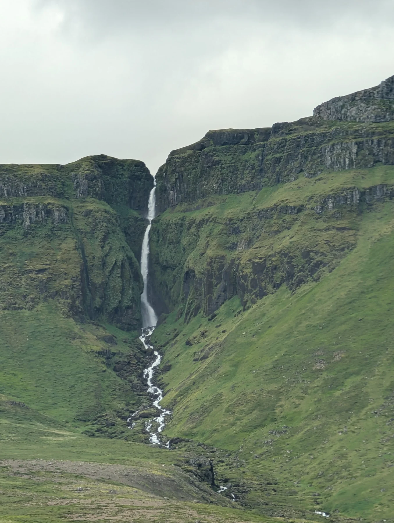 A narrow waterfall between green cliffs
