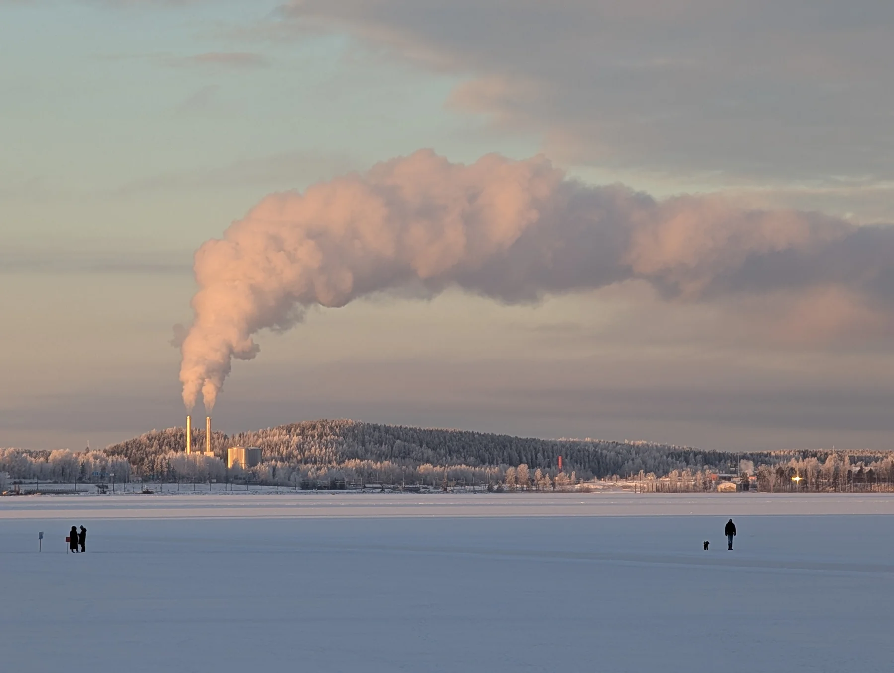 A winter industrial landscape beneath a plume of steam