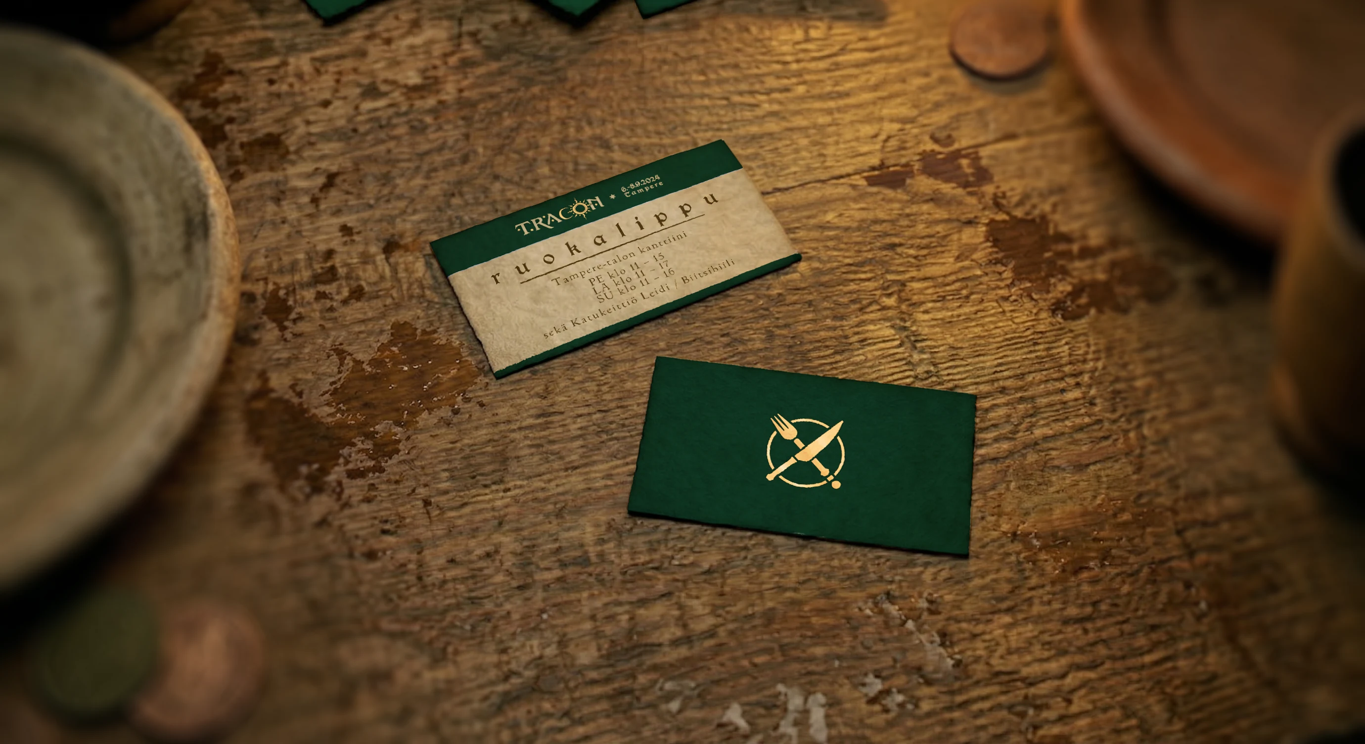 Front and back of a warm paper and forest green Tracon meal ticket design on a worn wooden table